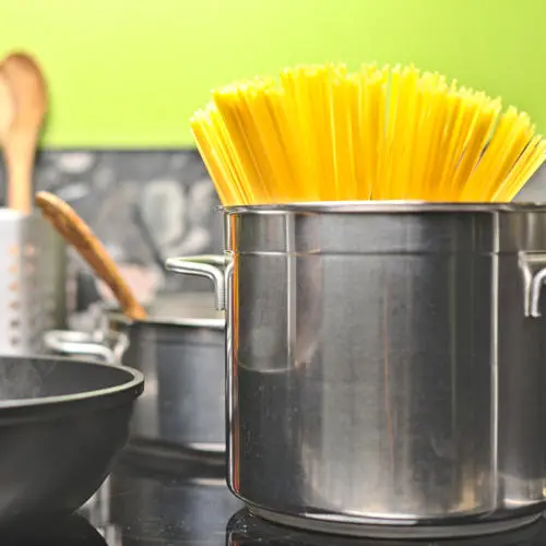 TwooDoo - Edelstahltopf mit Spaghetti neben gusseiserner Pfanne.
